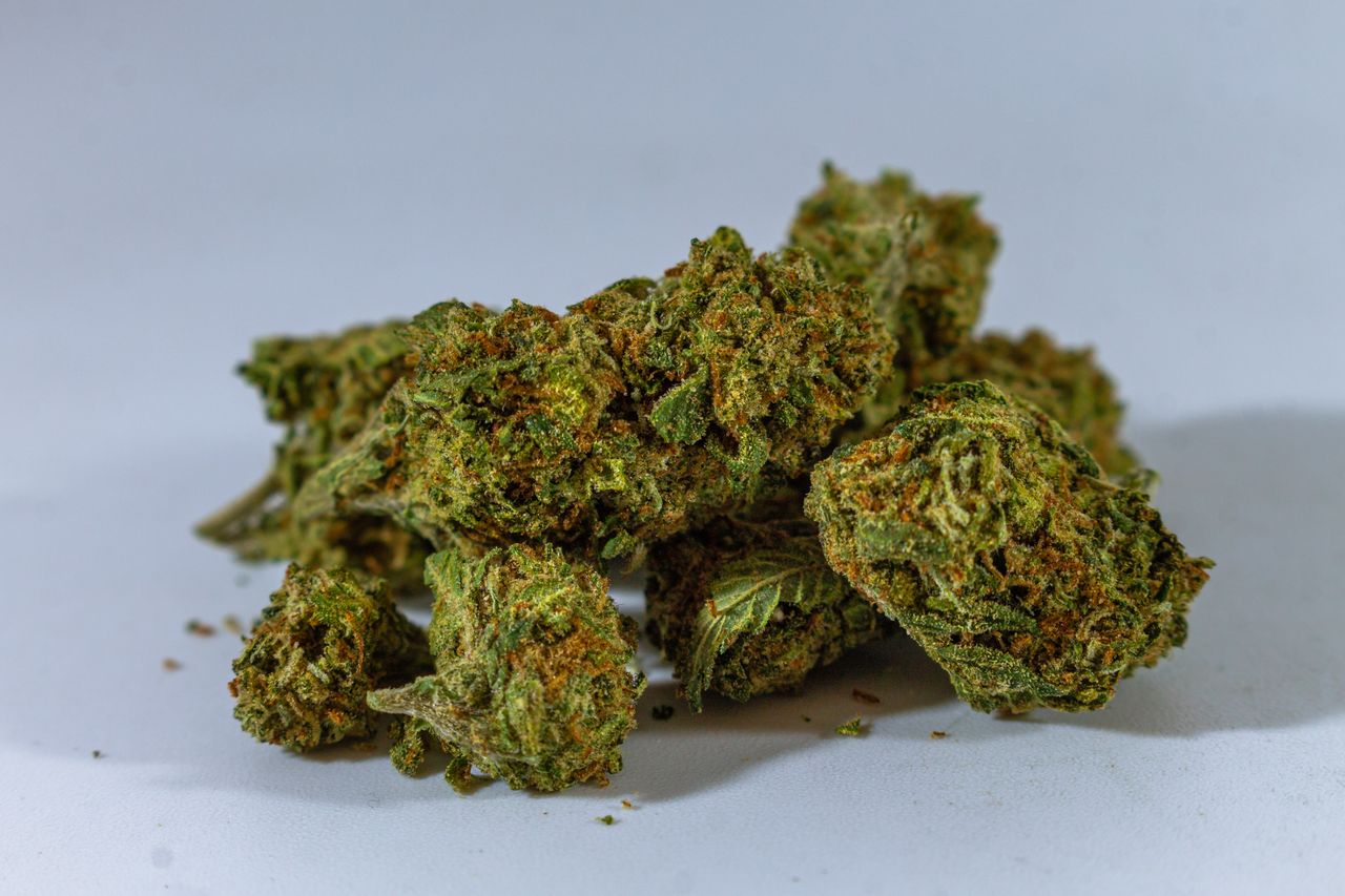 A detailed close-up of dried cannabis buds showcasing the texture and color, isolated on a white background.